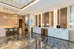 eine Lobby mit zwei Personen, die an der Rezeption stehen in der Unterkunft Atour Hotel Tonglu Fuchunjiang in Tonglu
