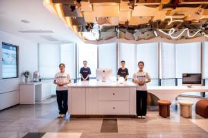 un grupo de personas de pie en un mostrador en una habitación en Atour Hotel Shenzhen Futian Xiangmi Lake, en Shenzhen