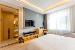 上海市にあるAtour Hotel Shanghai Pudong Jinqiao International Commercial Plazaのベッドとテレビが備わるホテルルームです。
