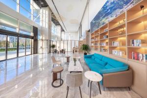 a library with a blue couch and tables and chairs at Atour Hotel Kunming Municipal Government Chunrong Street in Kunming