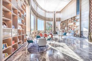 une bibliothèque avec des chaises et des étagères dans l'établissement Atour Hotel Zhuhai Jinwan Gaolan Port, 