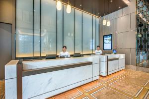 three people sitting at a reception desk in a lobby at Atour X Hotel Dongguan Chang'an Wanda in Dongguan