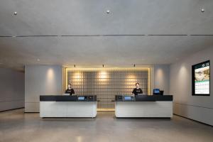 two people sitting at desks in a lobby at Atour Hotel Tianjin Zhongbei Haitai Industrial Park in Tianjin