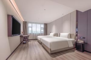 広州市にあるAtour X Hotel Guangzhou Baiyun International Airport Renhe Stationのベッド2台、薄型テレビが備わるホテルルームです。