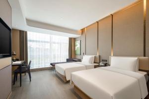a hotel room with two beds and a desk at Atour Hotel Xiamen Meifeng Binhai Romantic Line in Tong'an