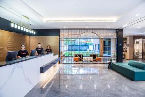 a lobby with three people sitting at a counter at Atour Hotel Hangzhou Wulin Plaza Baochu Road in Hangzhou