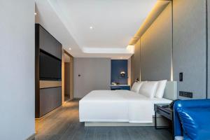 1 dormitorio con 1 cama blanca grande y TV en Atour Hotel Shaoxing Heqiao, en Shaoxing