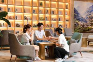 un grupo de personas sentadas alrededor de una mesa en una habitación en Atour Hotel Chongqing Guanyinqiao Flower Garden, en Chongqing