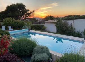 a swimming pool in a garden with a sunset in the background at MONTE LEONE in Bonifacio