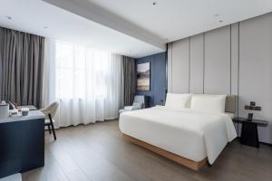 a bedroom with a large white bed and a desk at Atour X Hotel Zhuhai Gongbei Port High Speed Railway Station in Zhuhai