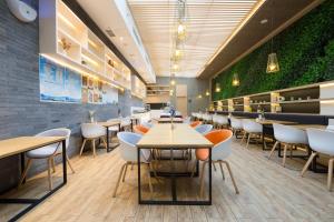 秦皇島的住宿－秦皇岛香玺海亚朵酒店，一间带桌椅和绿色墙壁的餐厅