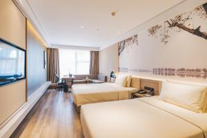 een hotelkamer met 2 bedden en een bank bij Atour Hotel Hangzhou Qianjiang New Town in Hangzhou