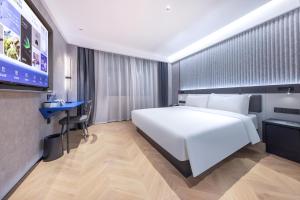 um quarto de hotel com uma grande cama branca e uma secretária em Atour Light Hotel Fuzhou Sanfang Qixiang em Fuzhou
