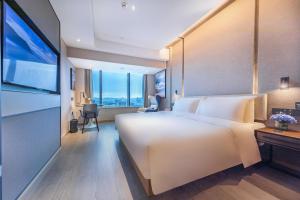 a hotel room with a large white bed and a television at Atour Hotel Shenzhen Guanlan High Tech Park in Lung Wa