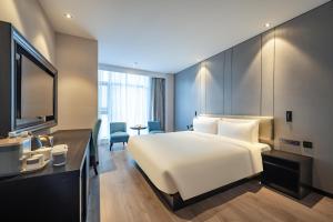 Atour X Hotel Hangzhou Binjiang Jiangnan Avenue في هانغتشو: غرفة في الفندق مع سرير أبيض كبير ومكتب