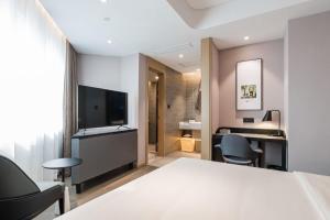 a hotel room with a bed and a desk and chairs at Atour Hotel Ningbo Gulou Tianyige in Ningbo