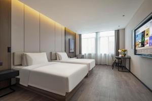 a hotel room with two beds and a flat screen tv at Atour Hotel Anji Longshan in Anji