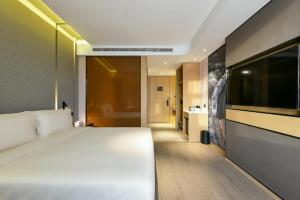 Atour Hotel Beijing Wangjing 798 Art District في بكين: غرفة نوم بسرير ابيض كبير وحمام