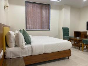 ein Schlafzimmer mit einem Bett, einem Tisch und einem Stuhl in der Unterkunft Hotel Heera Residency in Bhopal