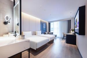 una camera d'albergo con due letti e una scrivania di Atour Hotel Nanjing Jinma Road Station a Nanjing