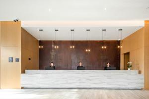 three men sitting at a large desk in a lobby at Atour Hotel Shanghai Minhang Industrial Park in Shanghai