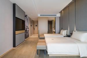 a hotel room with two beds and a tv at Atour Hotel Wuxi Coast City in Wuxi