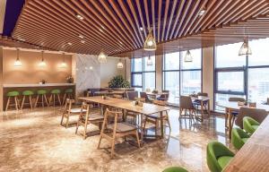 een restaurant met tafels, stoelen en ramen bij Atour Hotel Xining East Kunlun Road in Xining