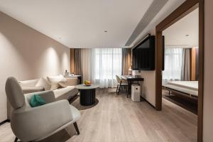 廈門市にあるAtour Hotel Xiamen Gaoqi Airport Chenggong Avenueのソファとベッド付きのホテルルーム