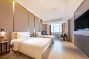 南昌市にあるAtour Hotel Nanchang West Railway Station International Expo Cityのベッド2台、薄型テレビが備わるホテルルームです。
