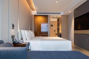 南昌市にあるAtour Hotel Nanchang West Railway Station International Expo Cityの大型ベッドとテレビが備わるホテルルームです。