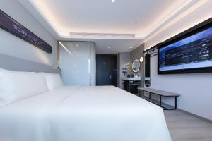 een slaapkamer met een groot wit bed en een televisie bij Atour Light Hotel Shanghai Pudong Zhangjiang Park Riverside in Shanghai