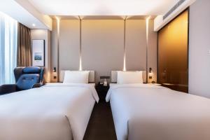 ein Hotelzimmer mit zwei Betten und einem blauen Stuhl in der Unterkunft Atour Hotel Ningbo Sanjiangkou Bund Book City in Ningbo + 39 Fotos