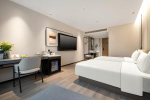 um quarto de hotel com uma cama branca e uma secretária em Atour Hotel Hangzhou Xintiandi Zhongda Intime em Hangzhou
