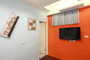 ein Zimmer mit einer orangefarbenen Wand und einem Flachbildfernseher in der Unterkunft Bears Line B&B train station in Hualien