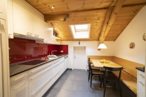 cocina con armarios blancos y techo de madera en Chasa Rontsch Madlaina, en Scuol