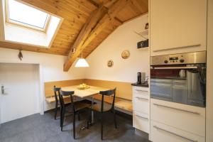 eine Küche mit einem Tisch und Stühlen sowie einem Fenster in der Unterkunft Chasa Rontsch Madlaina in Scuol