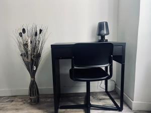 un bureau noir avec une chaise à côté d'un vase dans l'établissement Appartement cosy deux pièces proche centre ville de Marseille, à Marseille