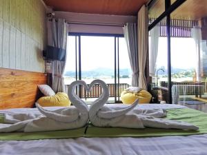 บ้านฮิมนาปัวรีสอร์ท في بوا: يوجد بجعتين على سرير مع مناشف