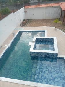 a swimming pool with blue tiles in a backyard at Casa de Veraneio em Itapema - BA in Santo Amaro