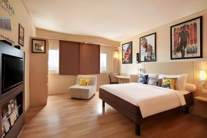 ein Hotelzimmer mit einem Bett und einem Flachbild-TV in der Unterkunft Ibis Jakarta Harmoni in Jakarta