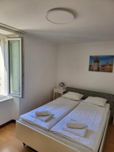 1 dormitorio con 1 cama blanca grande y toallas. en Bastis Central Guesthouse Lucerne City, en Lucerna