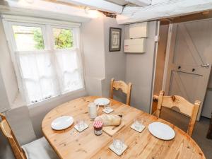 ein Esszimmer mit einem Holztisch und einem Fenster in der Unterkunft Cosy Cottage in Burford