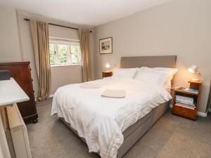 a bedroom with a large white bed and a window at Cosy Cottage in Burford