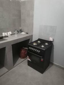 a small kitchen with a stove and a sink at Chez Manga in Ziguinchor