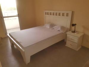 a bedroom with a white bed and a night stand at Chez Manga in Ziguinchor