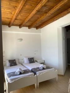 two beds in a bedroom with a wooden ceiling at Fisilanis Beachfront Hotel in Logaras