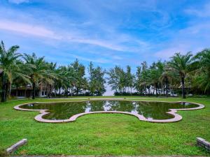 un parque con palmeras y una piscina reflectante en Lang Co Beach Resort, en Lang Co