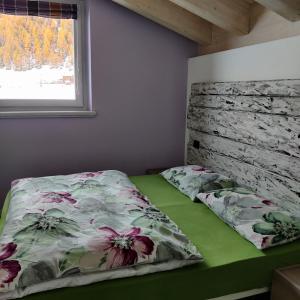 a bedroom with a bed with a floral comforter and a window at Al Dos in Livigno