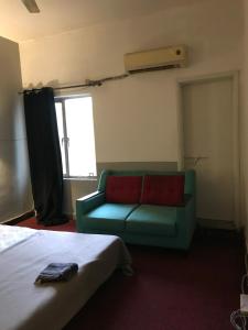 ein Wohnzimmer mit einem grünen Sofa und einem Fenster in der Unterkunft Durrani House in Islamabad