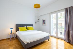 ein Schlafzimmer mit einem Bett mit gelben Kissen und einem Fenster in der Unterkunft Spacious Central Apt Downtown in Athen